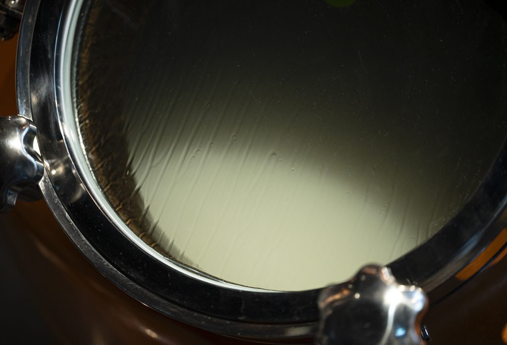 Milky white culture seen through a round sight glass on a steel still